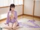 A woman in a purple kimono sitting on a bed.