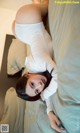 A woman laying on top of a bed in a white shirt.