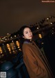 A woman in a brown coat standing on a bridge.