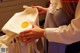 A woman holding a white bag with a gold seal on it.