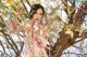 A woman in a floral dress posing in a tree.