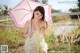 A woman in a white dress holding an umbrella.