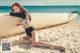 A woman in a bathing suit sitting on the beach next to a boat.