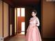 A woman in a pink dress standing in a hallway.