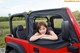 A woman sitting in the back of a red jeep.