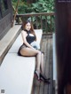 A woman sitting on a bench holding a fan.