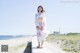 A woman in a kimono standing on a boardwalk by the ocean.